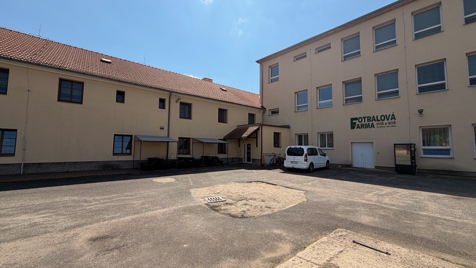 Zpevněný dvůr areálu s parkováním před budovou
