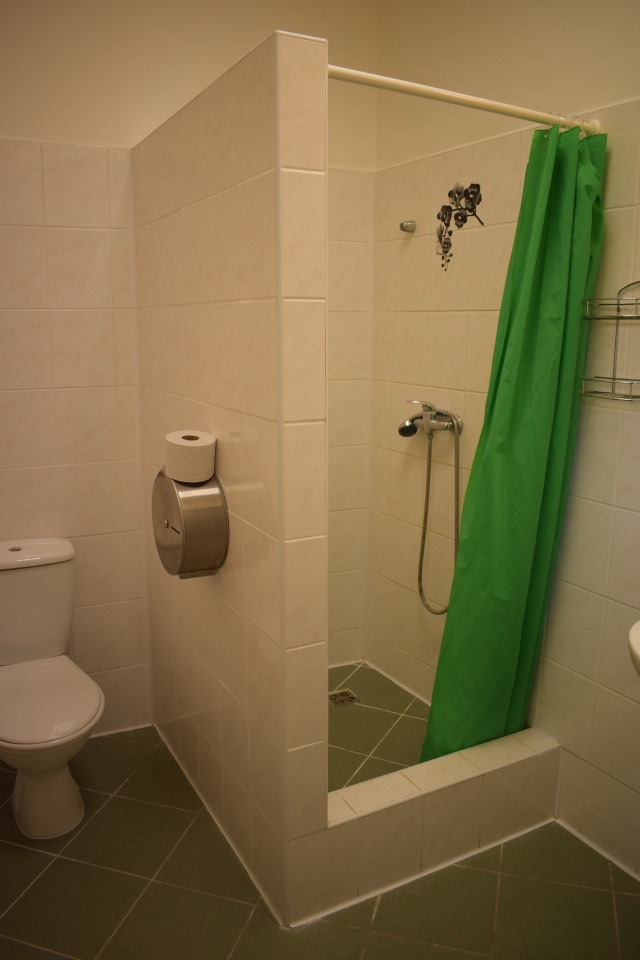Vlastní sociální zařízení apartmánu — WC a sprchový kout obložený bílým obkladem